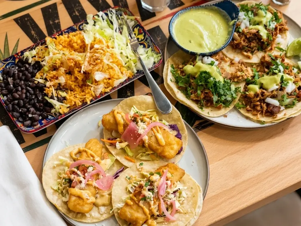 Table of fish and carnitas tacos with Mexican rice and black beans at MEXIKAN in Chappelle, Edmonton