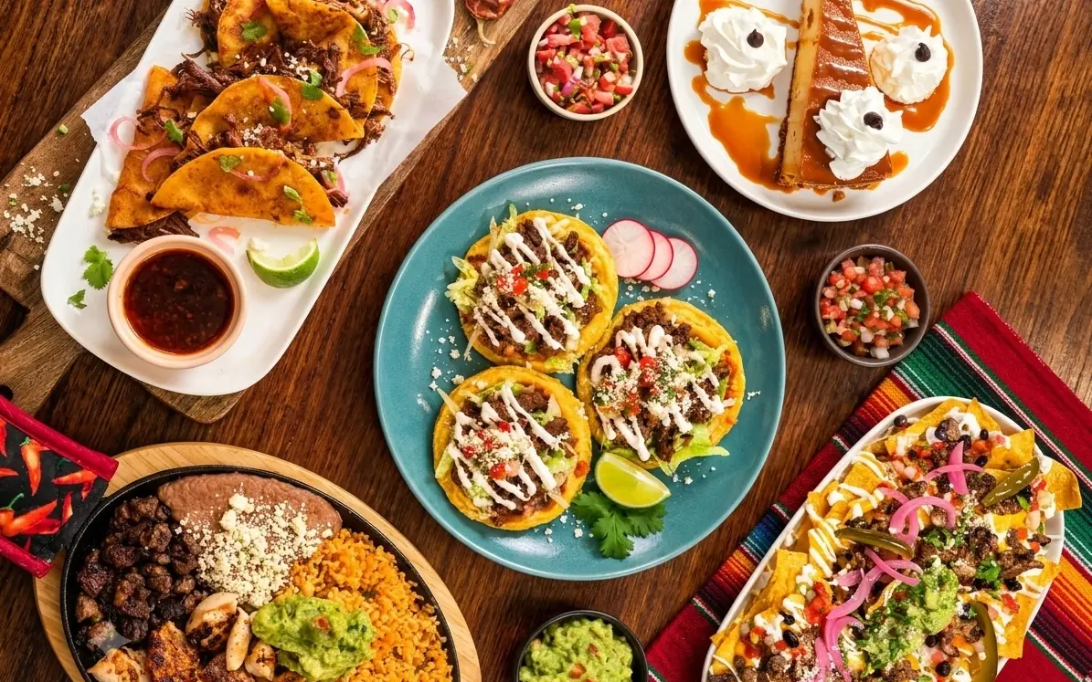 Birria tacos, beef tostadas, loaded nachos, a mixed grill skillet and a caramel dessert on one table at MEXIKAN in Heritage Valley, Edmonton