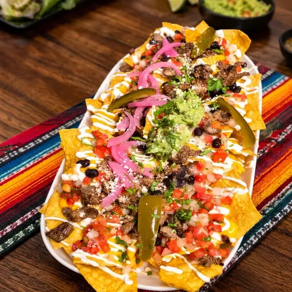 Loaded nachos with grilled beef, black beans, pickled onion, jalapeños, pico de gallo, guacamole and crema