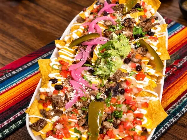 Loaded nachos with grilled beef, black beans, pickled onion, jalapeños, pico de gallo, guacamole and crema