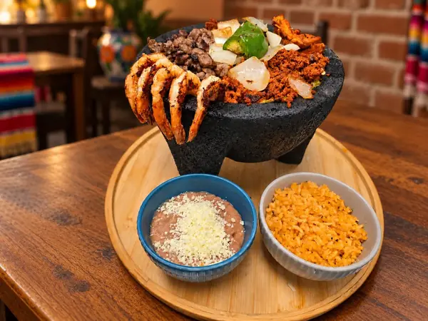 Molcajete Mixto with grilled steak, shrimp, peppers and onion, served with refried beans and Mexican rice at MEXIKAN in Heritage Valley, Edmonton