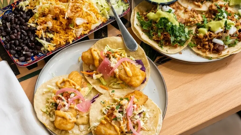 Table of fish and carnitas tacos with Mexican rice and black beans at MEXIKAN in Chappelle, Edmonton